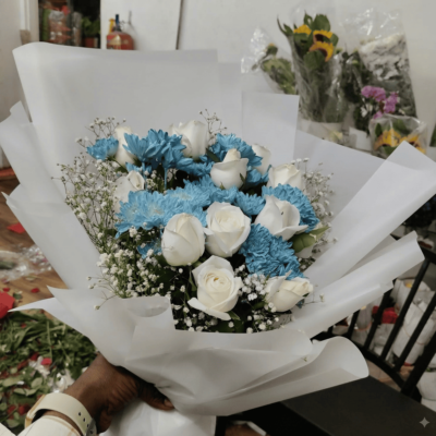 A 12 white roses and 6 blue daisies bouquet with baby's breath from GiftNexa Jaipur